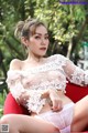 A woman in a white lingerie sitting on a red chair.