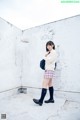 A woman in a school uniform standing in a bathroom.