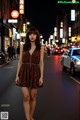 A woman standing in the middle of a city street at night.