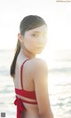 A woman in a red bikini standing on the beach.