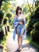 A woman in a blue kimono is walking down a path.