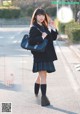 A woman in a school uniform is walking down the street.