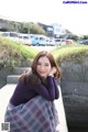 A woman in a purple sweater and plaid skirt posing for a picture.