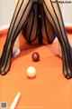 A woman in fishnet stockings is playing pool. 