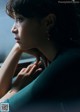 A woman looking out of a window with her hand on her chin.