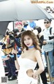 A woman in a white dress holding an umbrella.