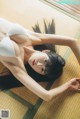 A woman laying on a tatami mat in a white bra.