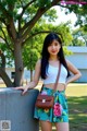 A woman in a white top and floral skirt posing for a picture.