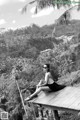 A woman sitting on a wooden platform in the middle of a jungle.