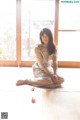 A woman sitting on the floor in front of a window.