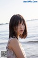 A woman standing on a beach next to the ocean.