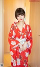 A woman in a red kimono standing in front of a door.