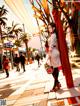 A woman in a white coat is walking down the street.