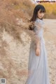 A woman in a blue dress standing in the sand.