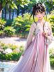 A woman in a pink and white dress standing in a park.