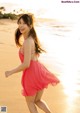 A woman in a pink dress running on the beach.