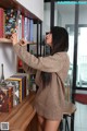 A woman standing in front of a bookshelf filled with books.