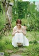 A woman in a white dress sitting in the grass.