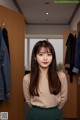 A woman standing in front of a rack of clothes.