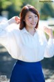 A woman in a white shirt and blue skirt posing for a picture.