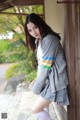 A woman in a school uniform leaning against a wall.