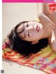 A woman laying on top of a colorful towel on the beach.