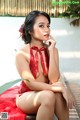 A woman in a red lingerie sitting on a bench.