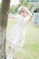 A young girl in a white dress leaning against a tree.