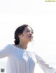 A woman in a white blouse standing on a beach.